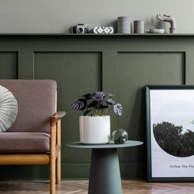 Stylish interior design of living room at cozy apartment with stylish sofa, plants, design furnitures, decoration and elegant accessories. Mock up poster frames on the shelf.  Home staging.