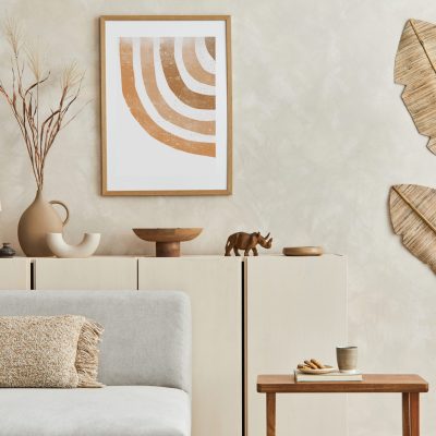 Stylish living room composiiton with mock up poster frame, grey sofa, wooden furnitutre and personal accessories. Pastel neutral colours. Template.